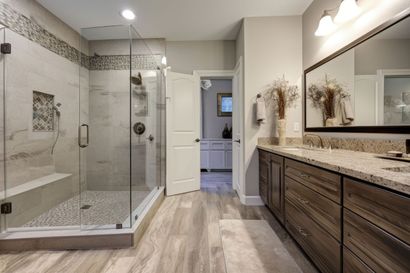 Modern bathroom with glass shower, freestanding tub, and wood vanity with large mirror.