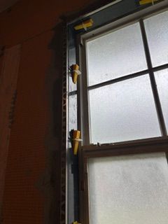 Partially open window with a yellow clamp on the frame in a dim room