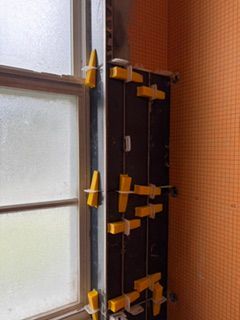 Frosted window beside stacked yellow clamp-like tools on a dark wooden cabinet in a room