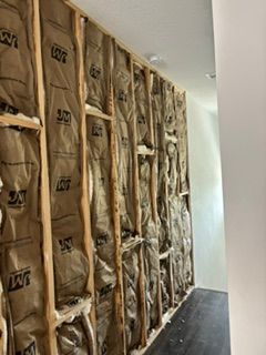 Insulated wall framing along a narrow hallway under construction, with exposed brown insulation panels.