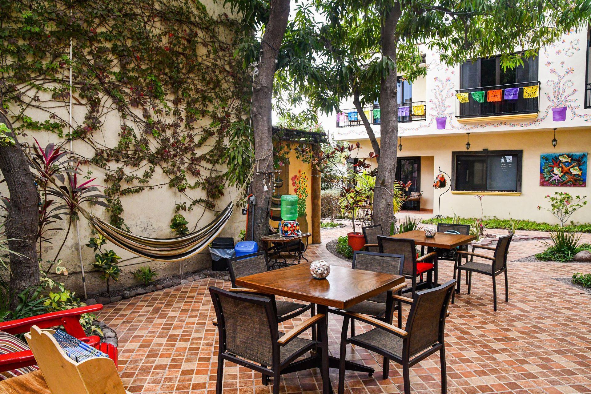 A patio with tables and chairs and a hammock.