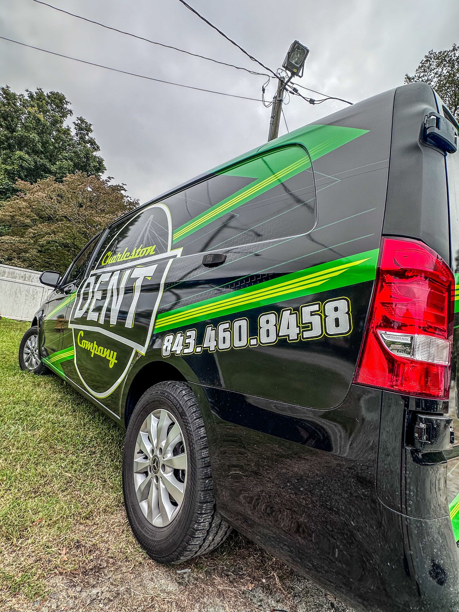 The side of a black Mercedes metris van displaying charleston dent company logo and phone number