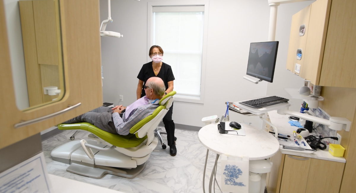 Dentist assisting patient in a dental chair in a bright, modern office.