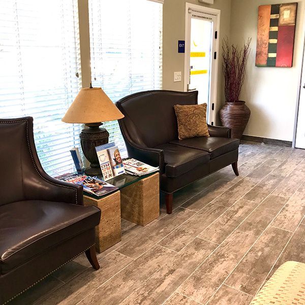 A waiting room with a couch, chairs, and a lamp