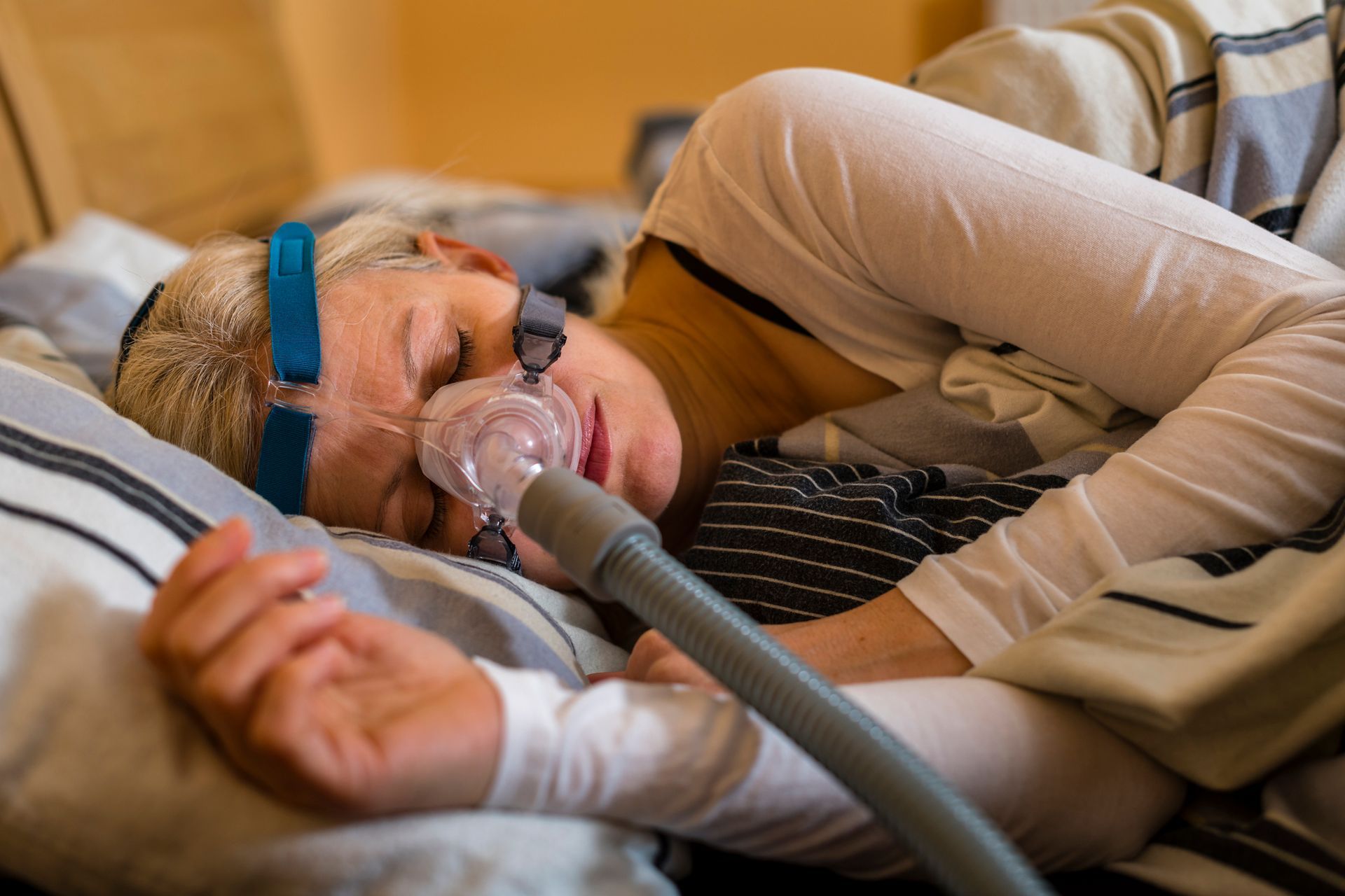 A woman is sleeping with an oxygen mask on her face.