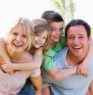 A family is posing for a picture with a man carrying two children on his back A family is posing for a picture with a man carrying two children on his back