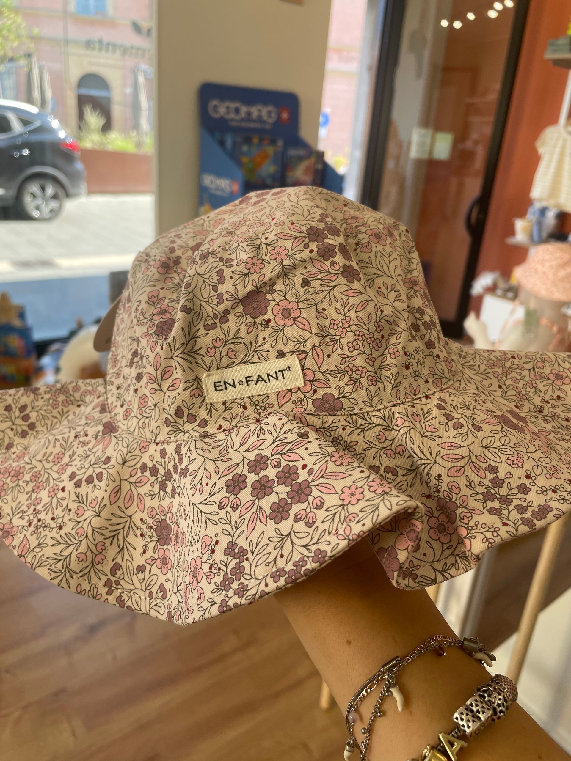 Cappello da sole floreale a tesa larga esposto su una mano di manichino nella vetrina di un negozio