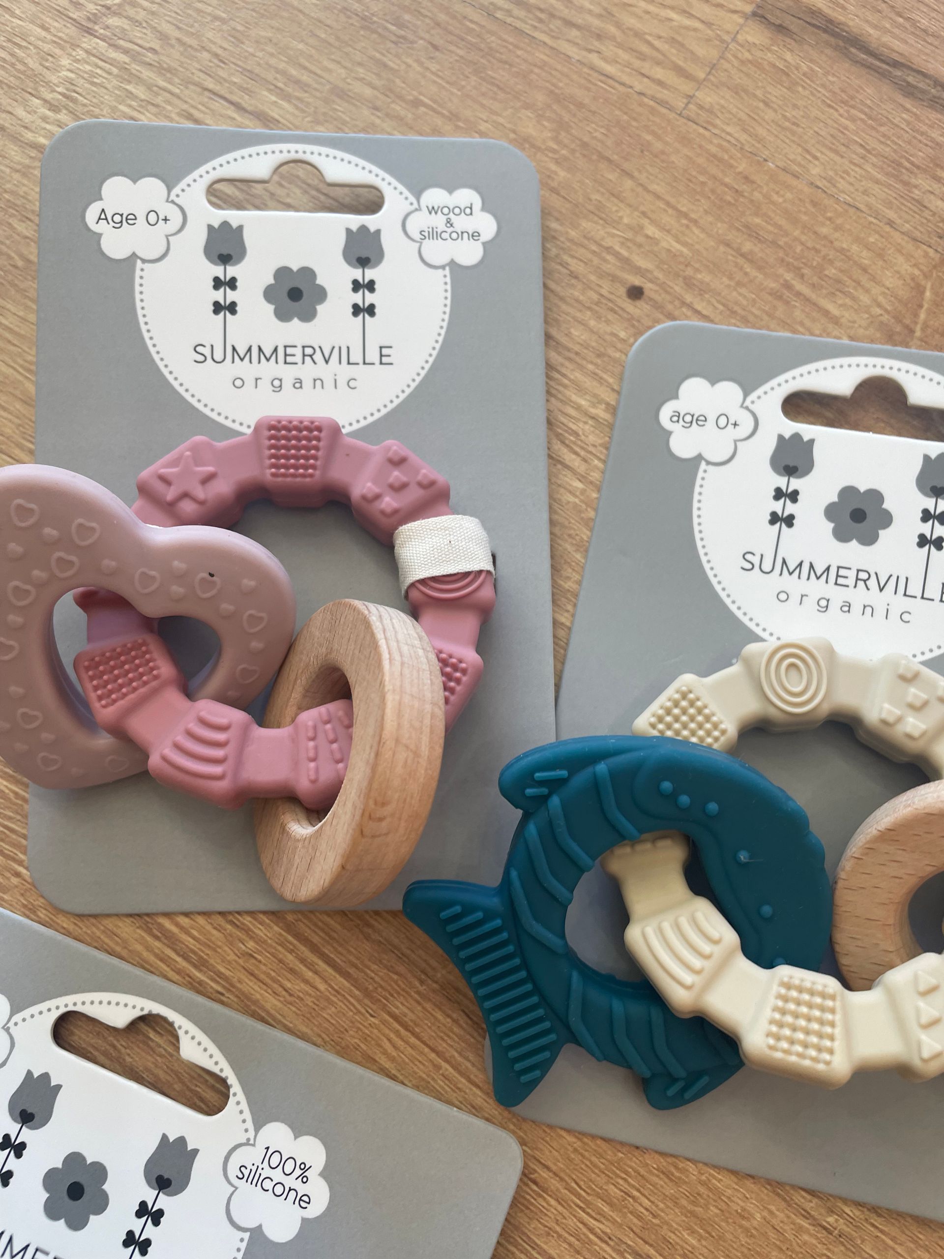 Massaggiagengive a forma di cuore color pastello su cartoncini espositivi, in rosa, beige e verde acqua, su una superficie di legno
