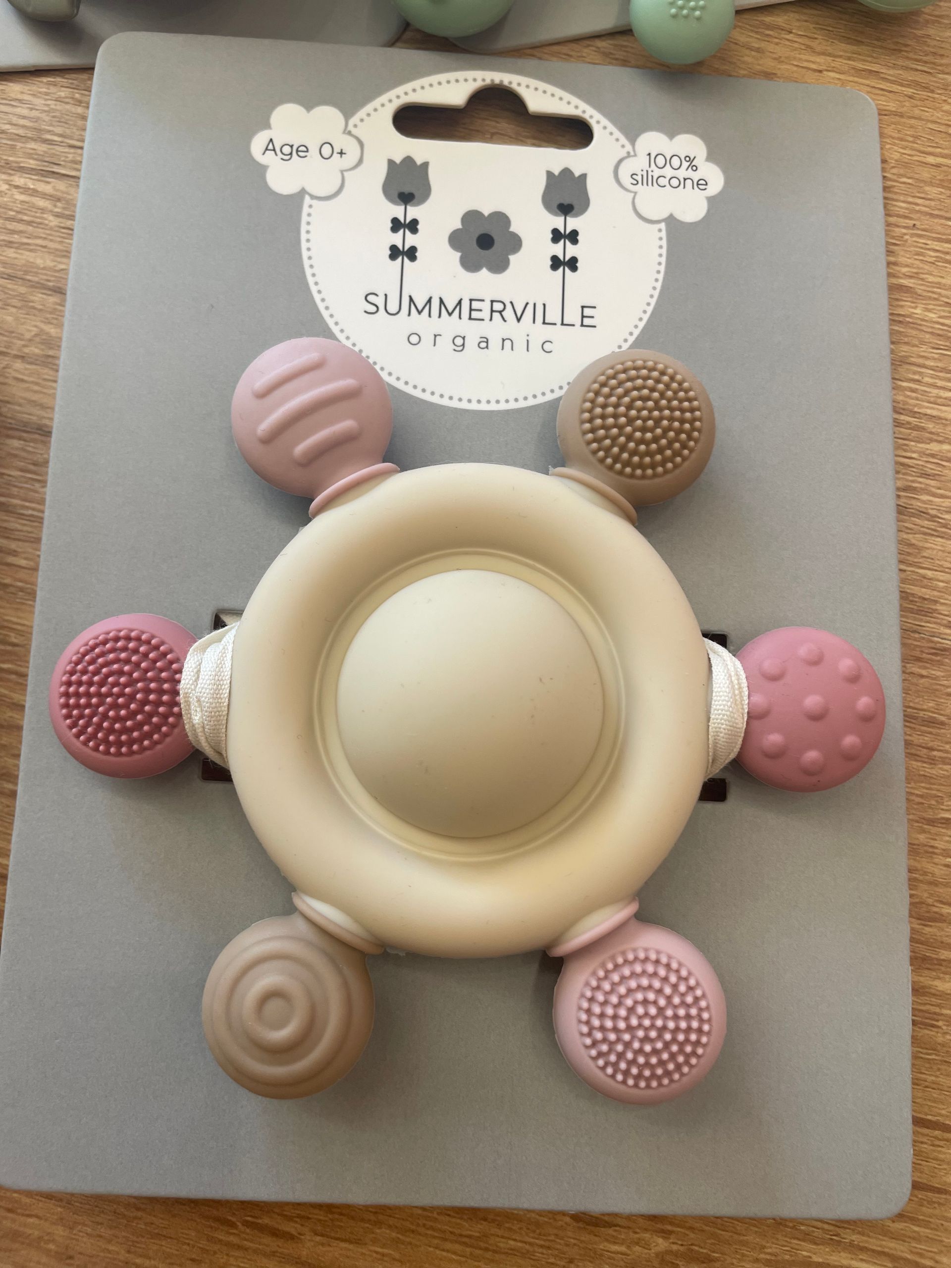 Pannello grigio con un giocattolo antistress in silicone beige e sei popper testurizzati dai colori pastello disposti intorno