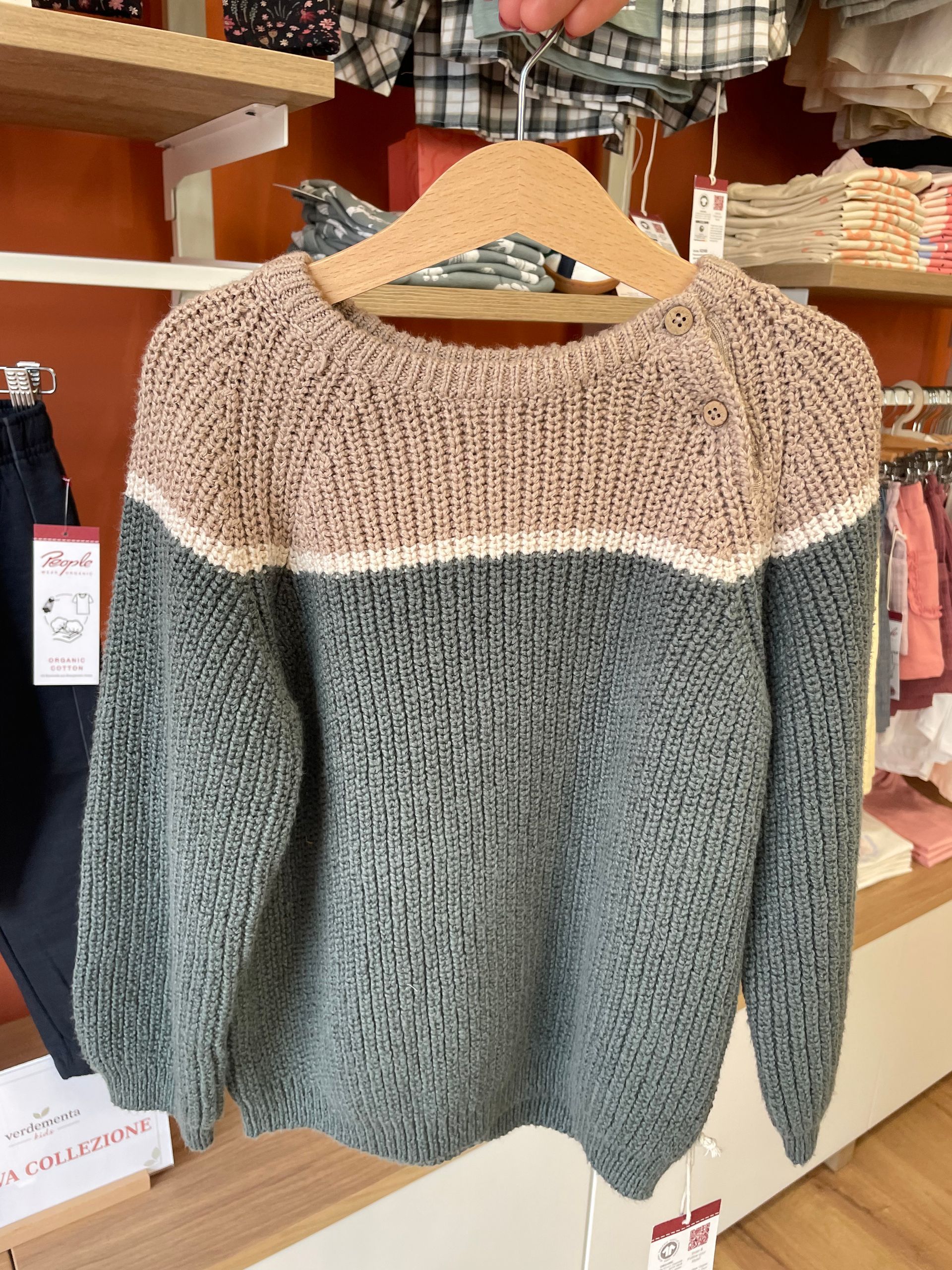 Maglione in maglia bicolore appeso a una gruccia in un’esposizione in negozio