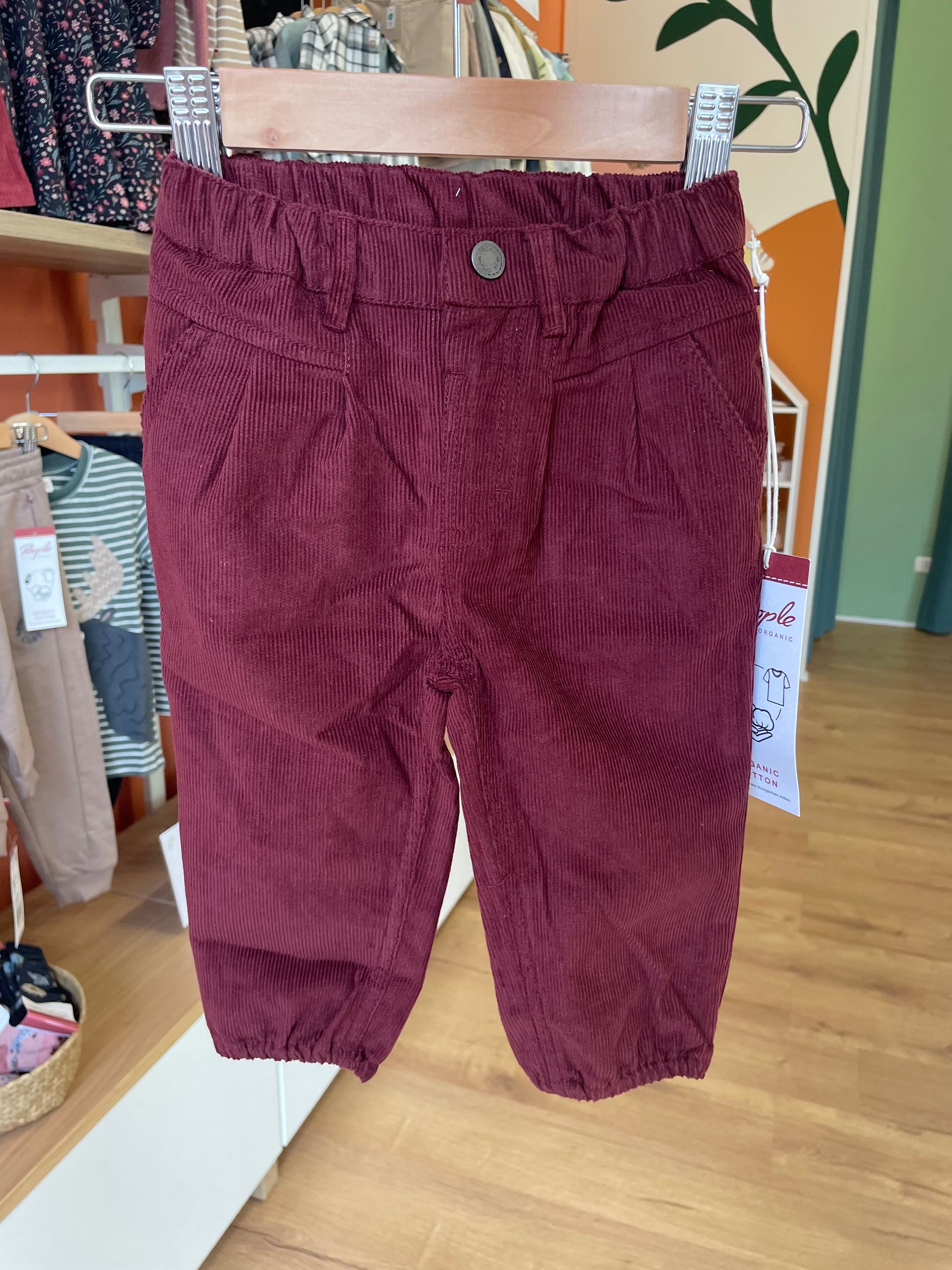 Pantaloni jogger bordeaux testurizzati appesi a uno scaffale in un negozio di abbigliamento