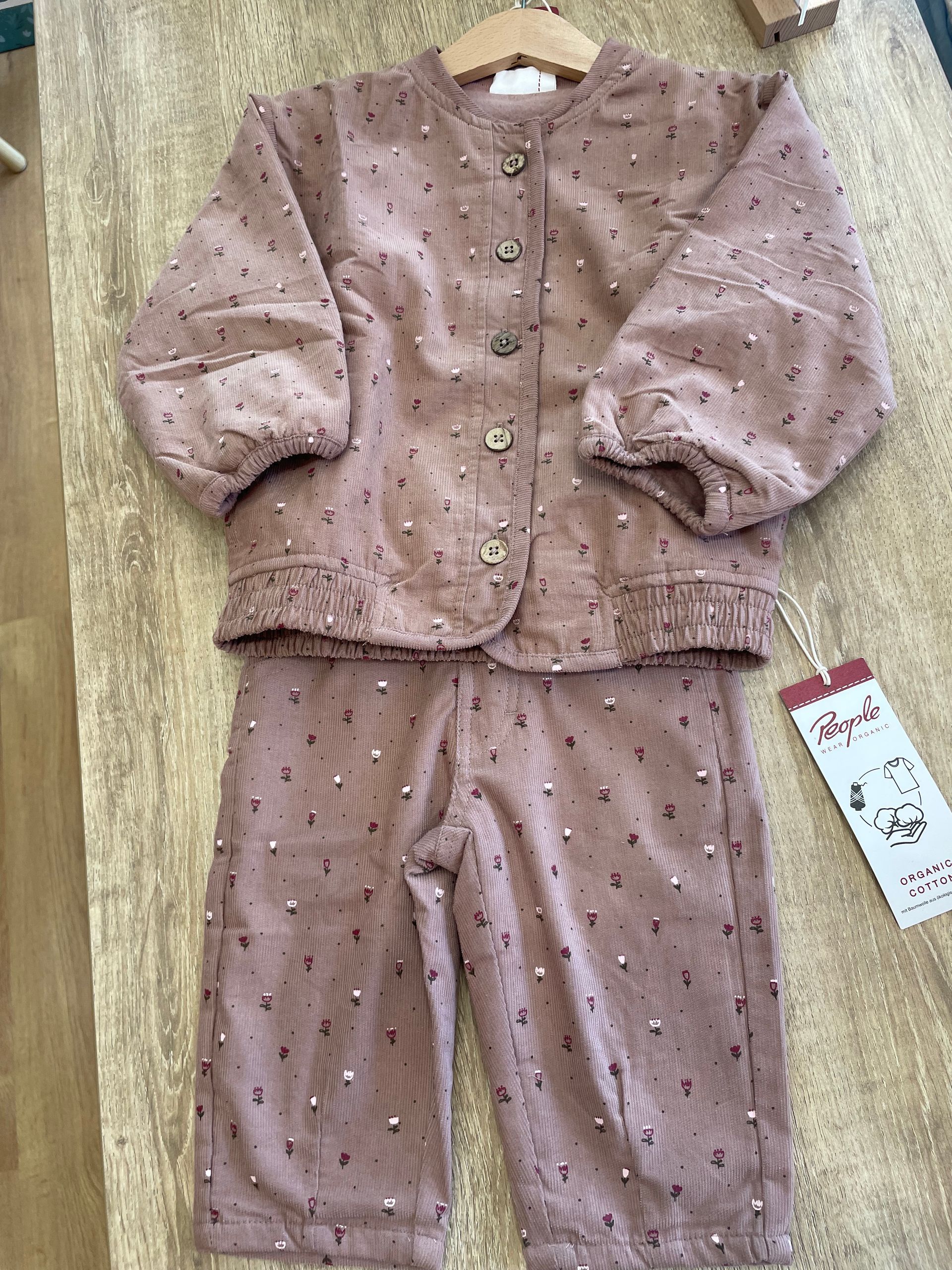 Completo rosa ricamato per bambini, con maglia a maniche lunghe e pantaloni coordinati, appeso a una gruccia