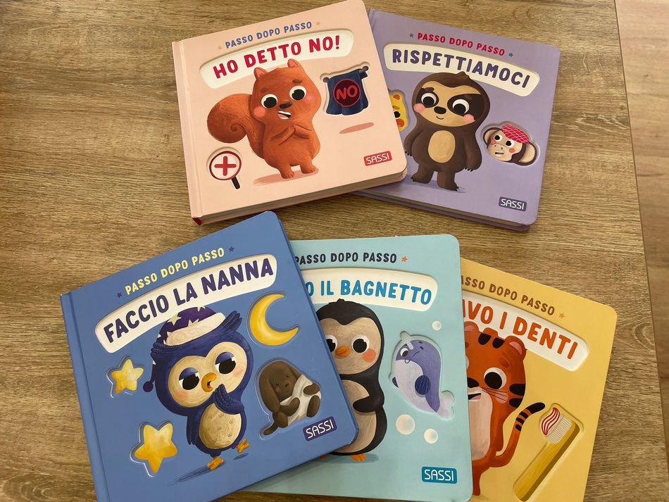 Cinque libri illustrati e colorati per bambini in italiano sul lavarsi i denti e fare il bagno, disposti su un pavimento di legno
