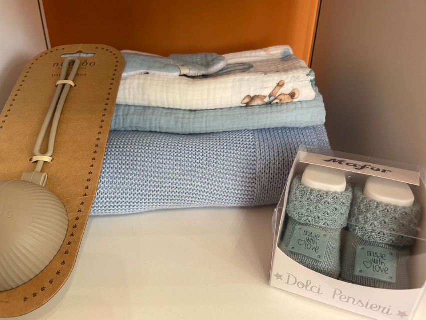 Asciugamani piegati e accessori da bagno su uno scaffale, tra cui una spugna esfoliante marrone chiaro e un piccolo contenitore con coperchio trasparente.