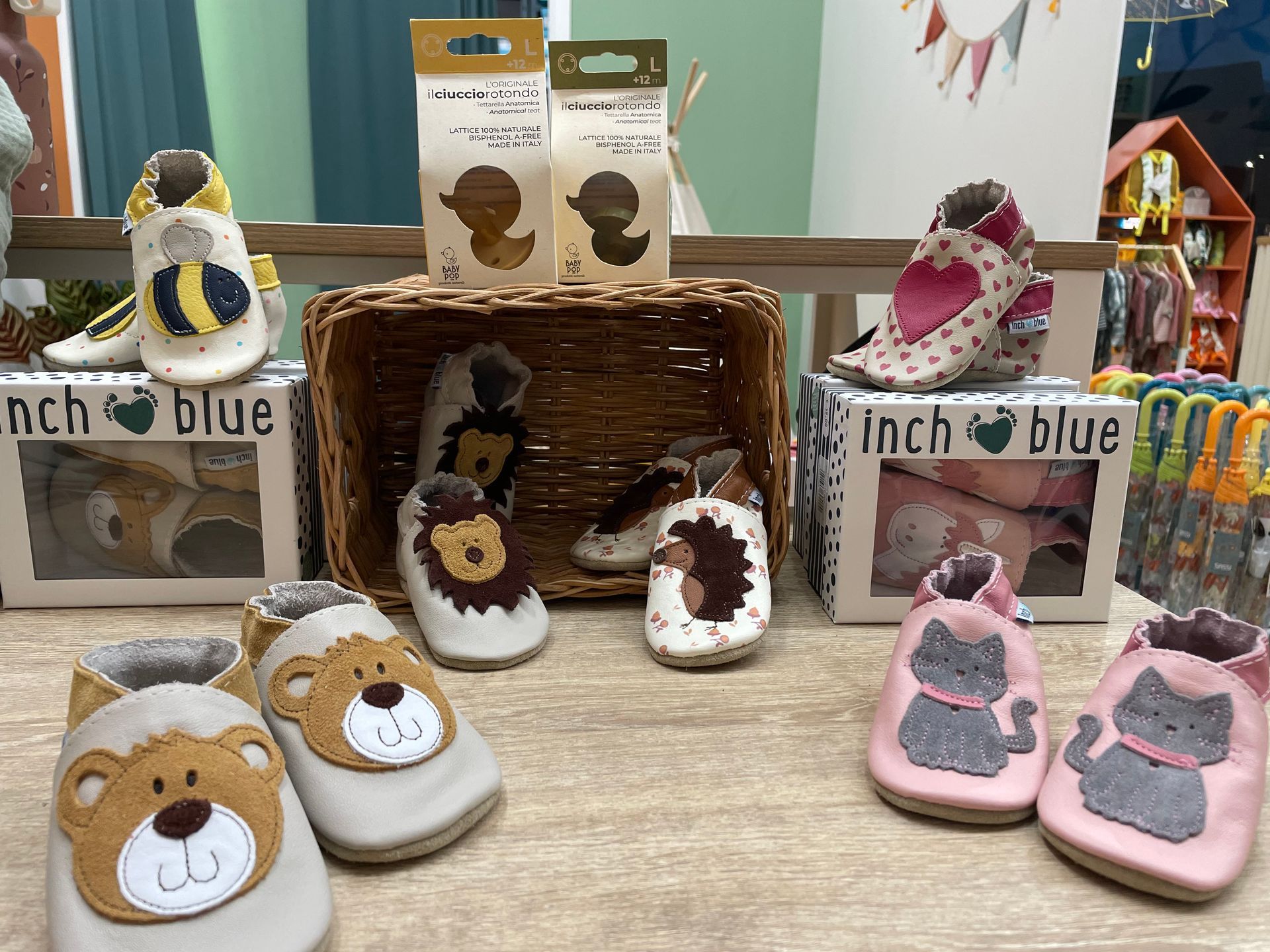 Scarpe e pantofole per bambini, fatte a mano e decorate con animaletti, esposte su un tavolo a una fiera dell’artigianato