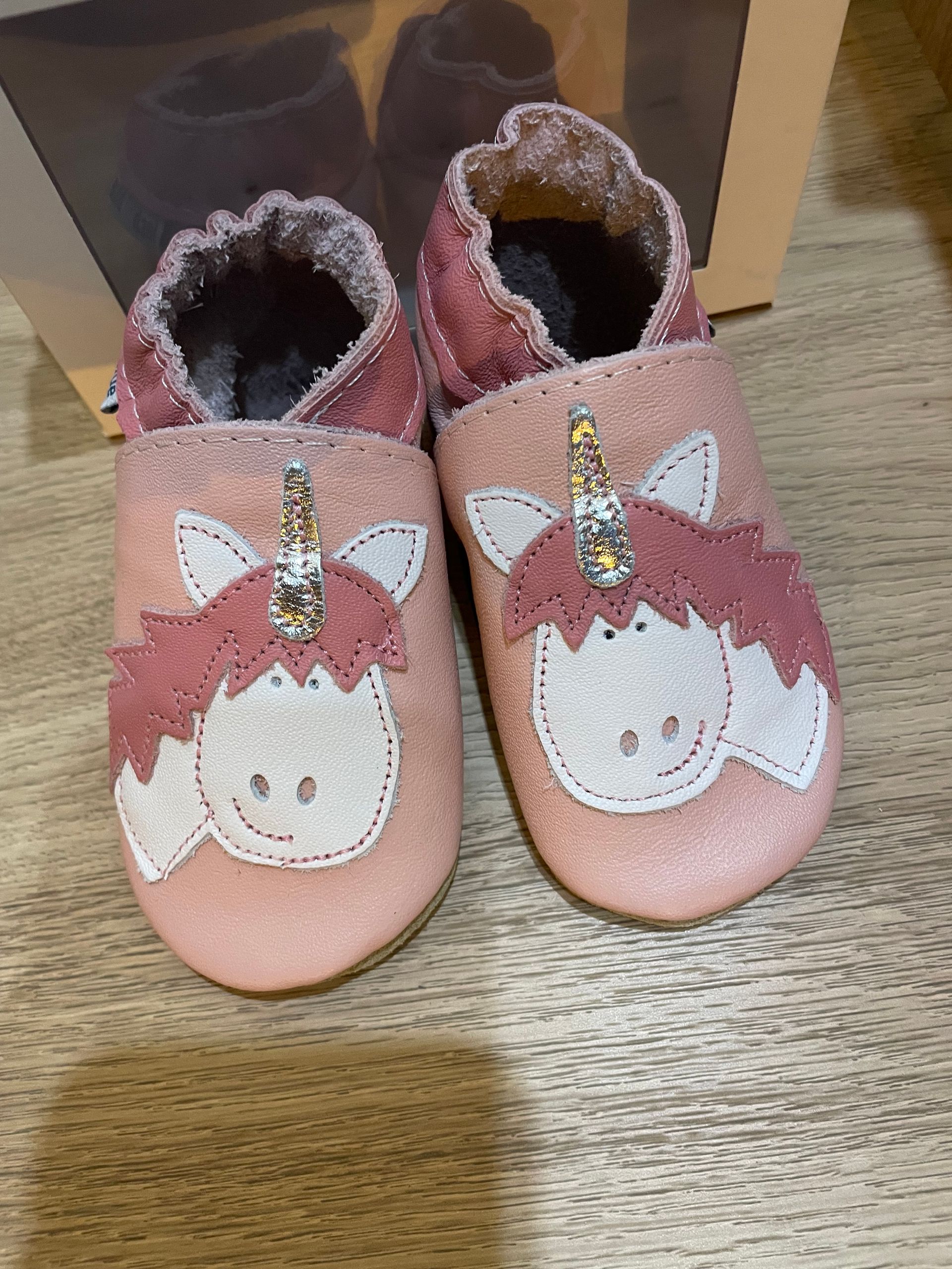 Scarpe rosa da bambina con faccine e fiocchi, su un pavimento di legno