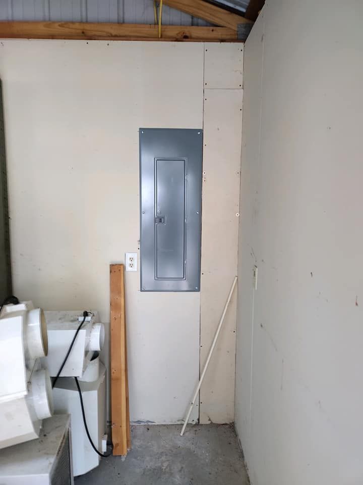 A room with a washer and dryer and a electrical box on the wall.