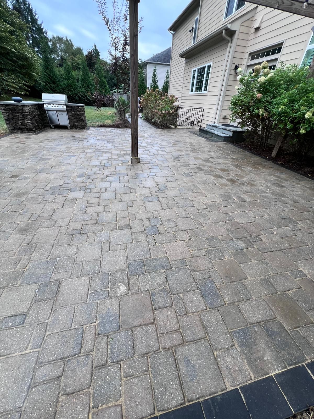 Brick patio with a grill and house in the background.