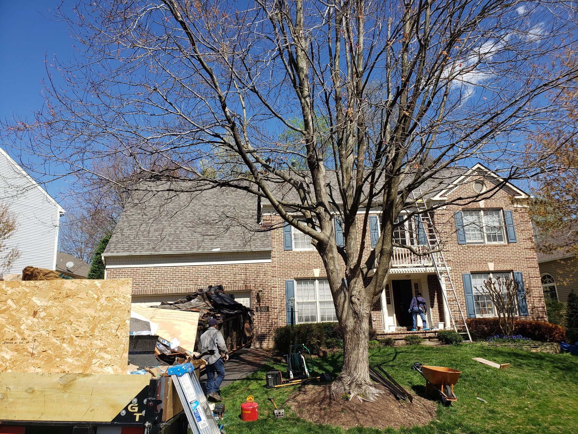 A man is standing in front of a house with a tree in front of it.