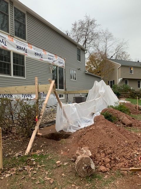 A large pile of dirt is in front of a house under construction.