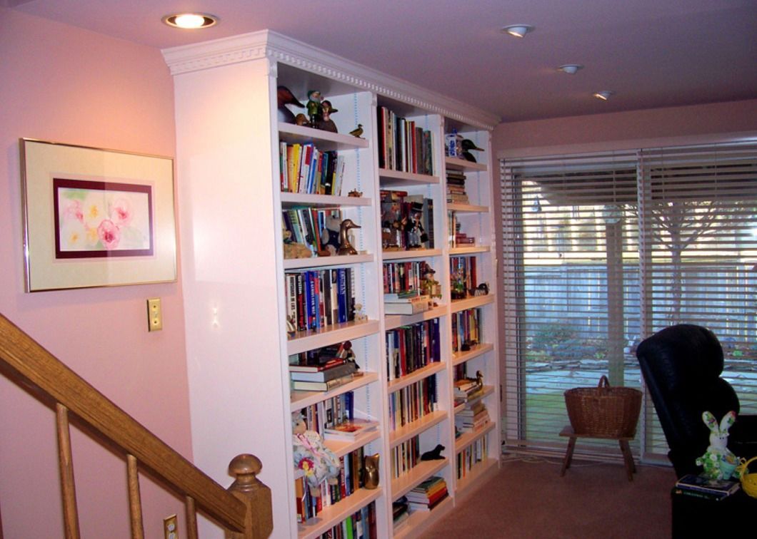 A living room with a staircase and lots of bookshelves