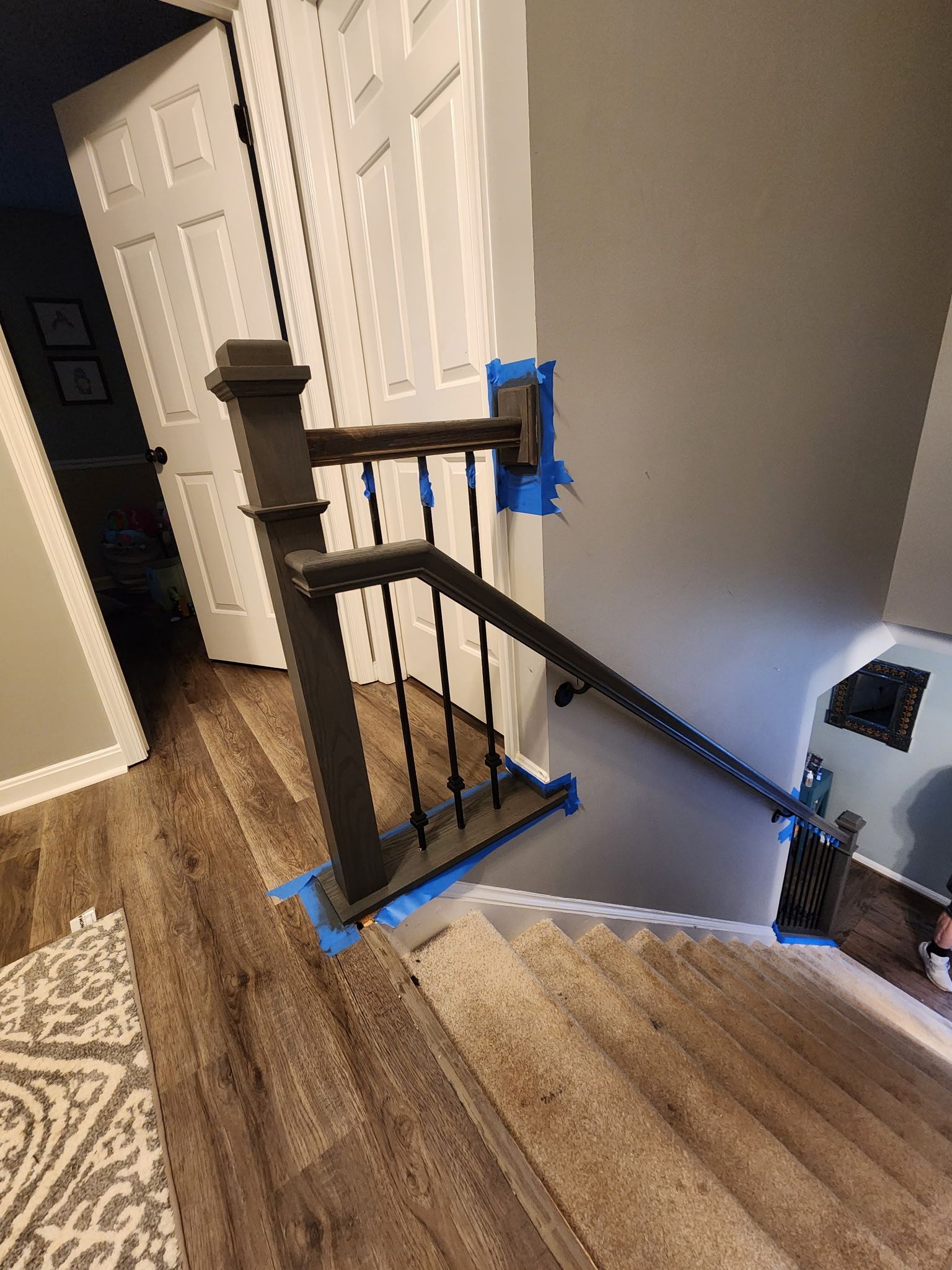 A staircase with brown wooden steps, black railing, and gray walls, inside a home.