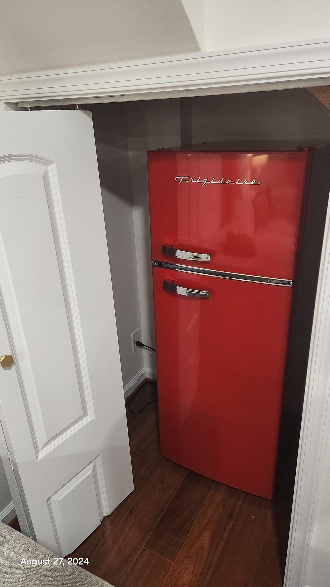 Red retro-style refrigerator in a small space next to a white door.