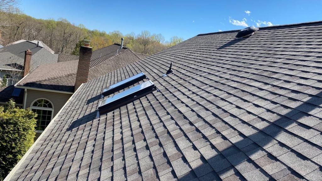 A roof with two skylights on it and a blue sky in the background.