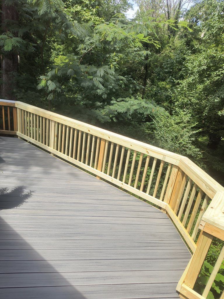 Wooden boardwalk with yellow railing curving through a lush green forest