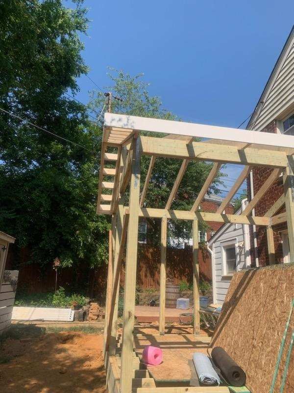 A wooden structure is being built in the backyard of a house.