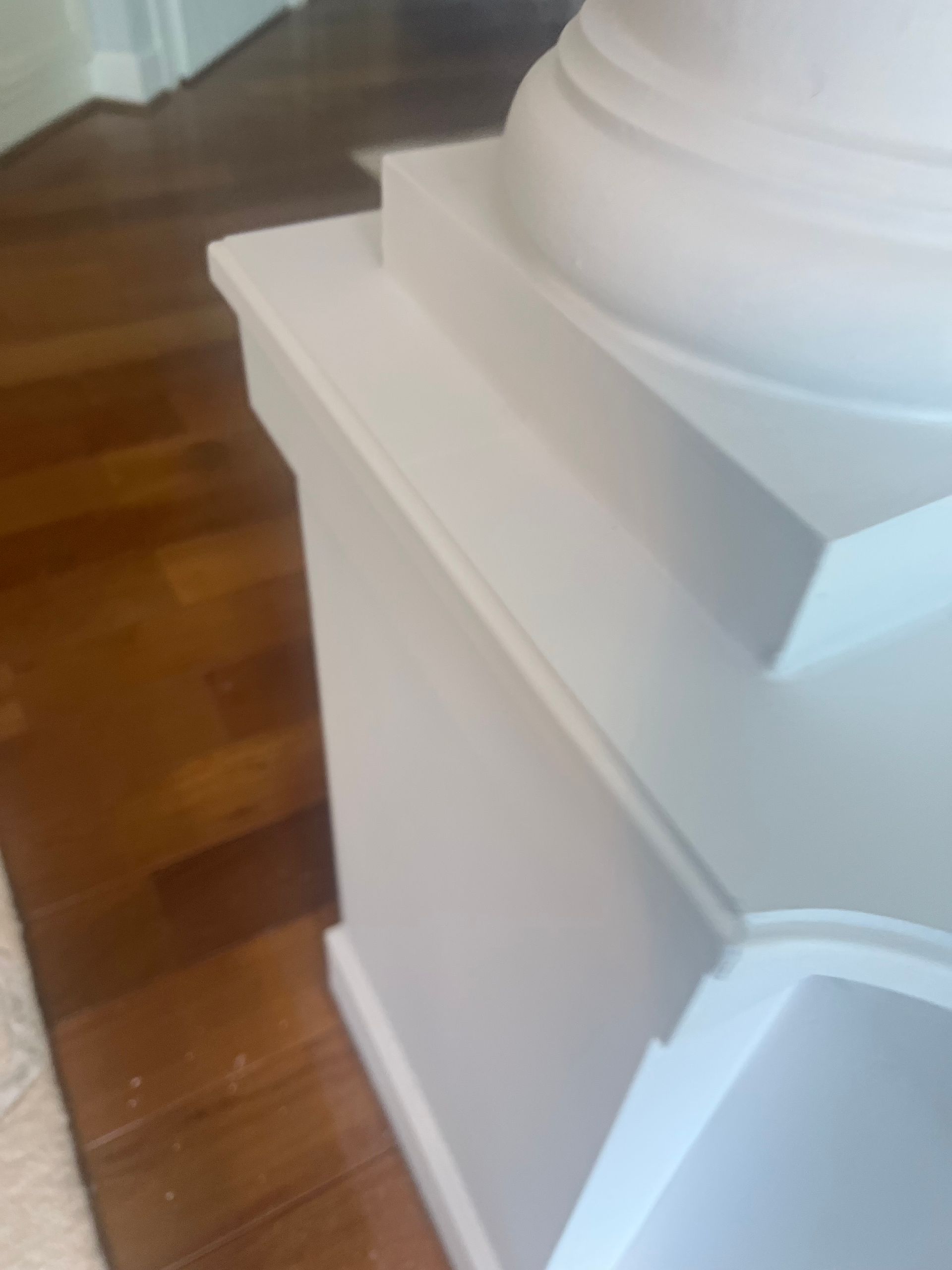 White staircase trim and base molding beside a polished wooden floor