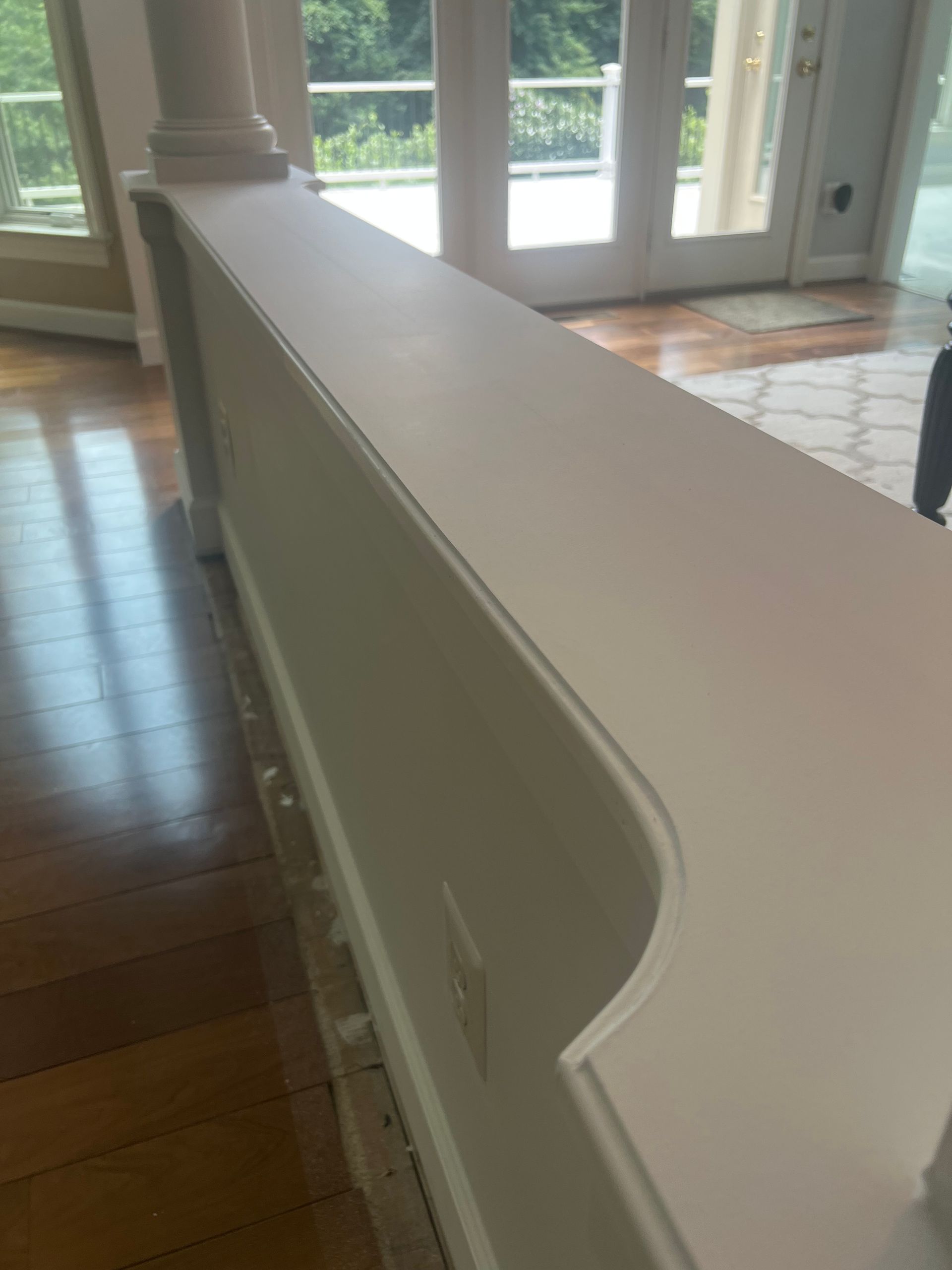 White stair railing in a bright hallway with hardwood floors and glass doors