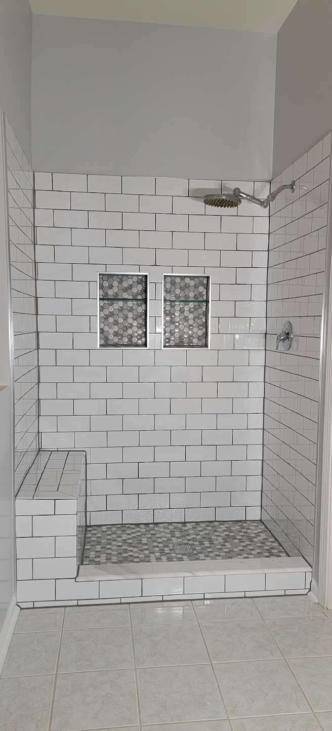 A bathroom with a walk in shower and a bench.
