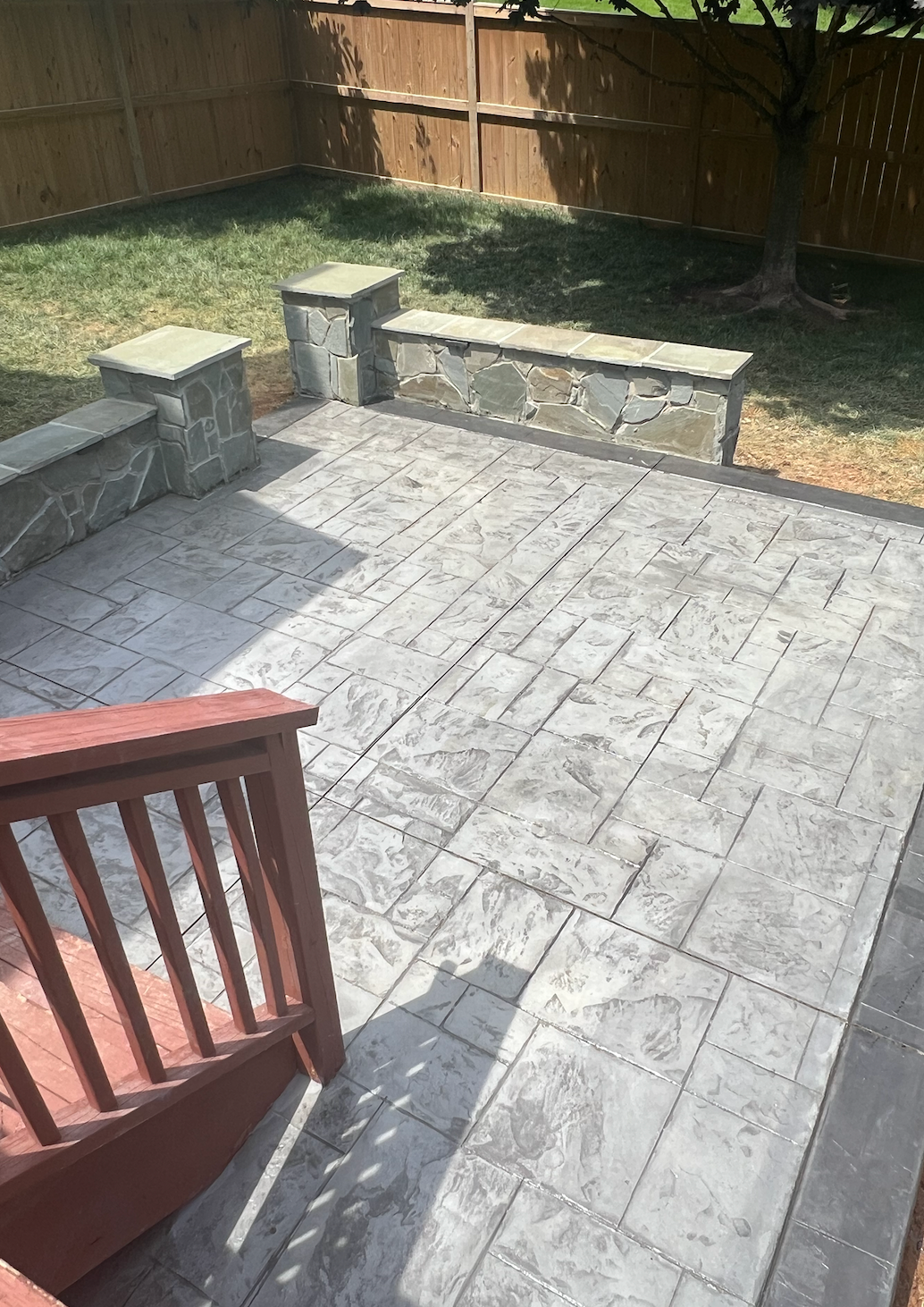 A patio with a rocking chair and a bench in the backyard.