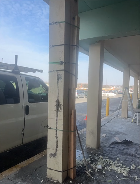 A white van is parked next to a concrete pillar