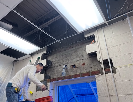 A man is working on a brick wall in a room.