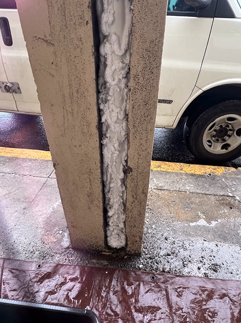 A white van is parked next to a concrete post with foam on it.