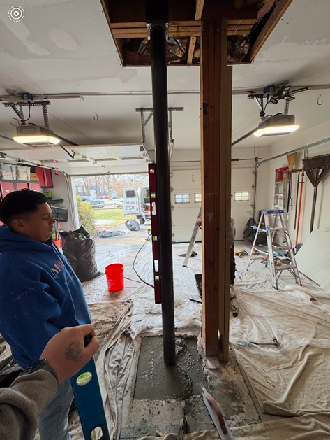 A man is standing in a garage holding a level.