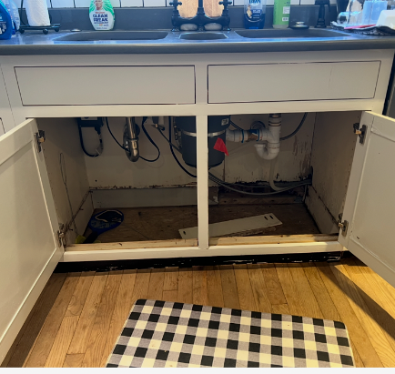 The underside of a kitchen sink with the doors open