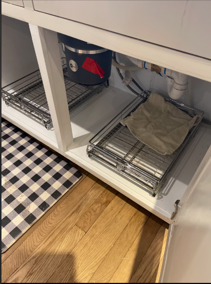 Under a kitchen sink is a tray with a towel on it