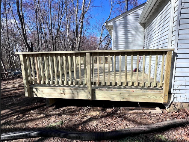A wooden deck is sitting in front of a white house.