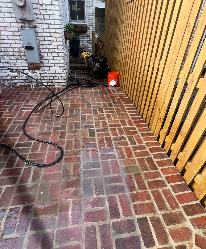 A brick walkway is being cleaned with a pressure washer.