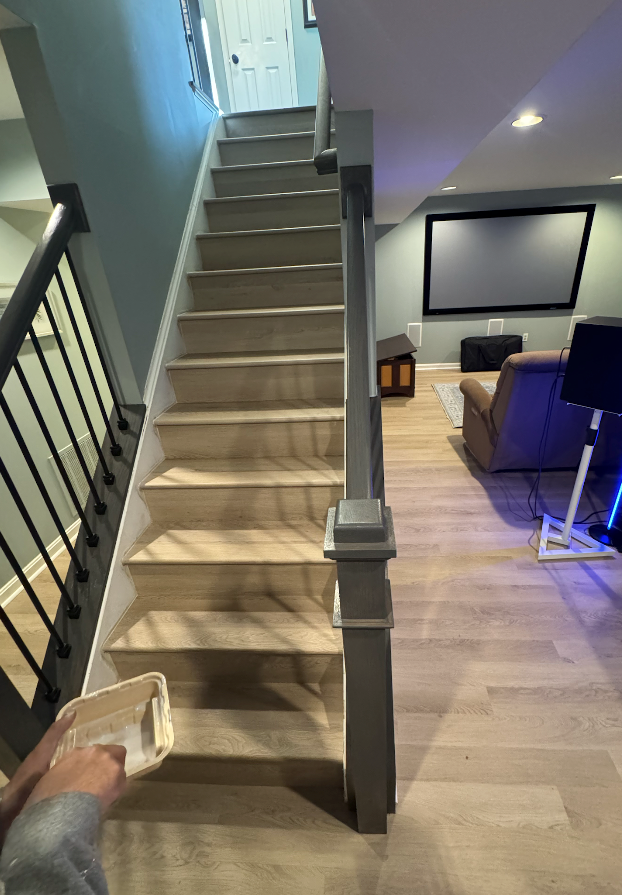 A person is standing next to a set of stairs in a living room.
