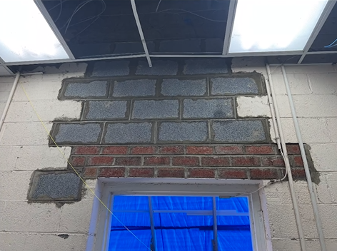 A brick wall with a window in the middle of it