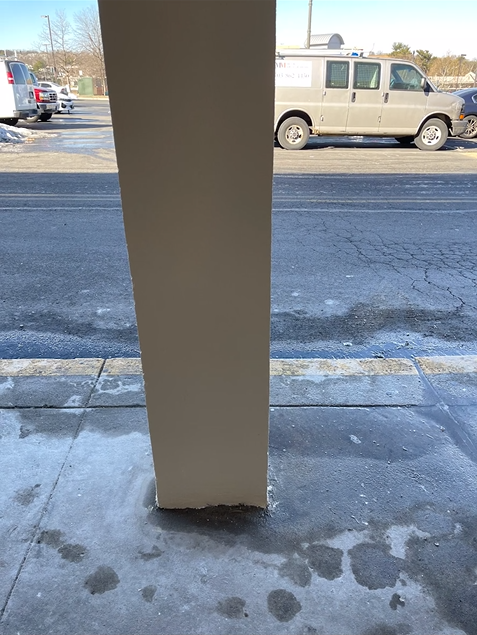 A van is parked on the side of the road next to a pillar.