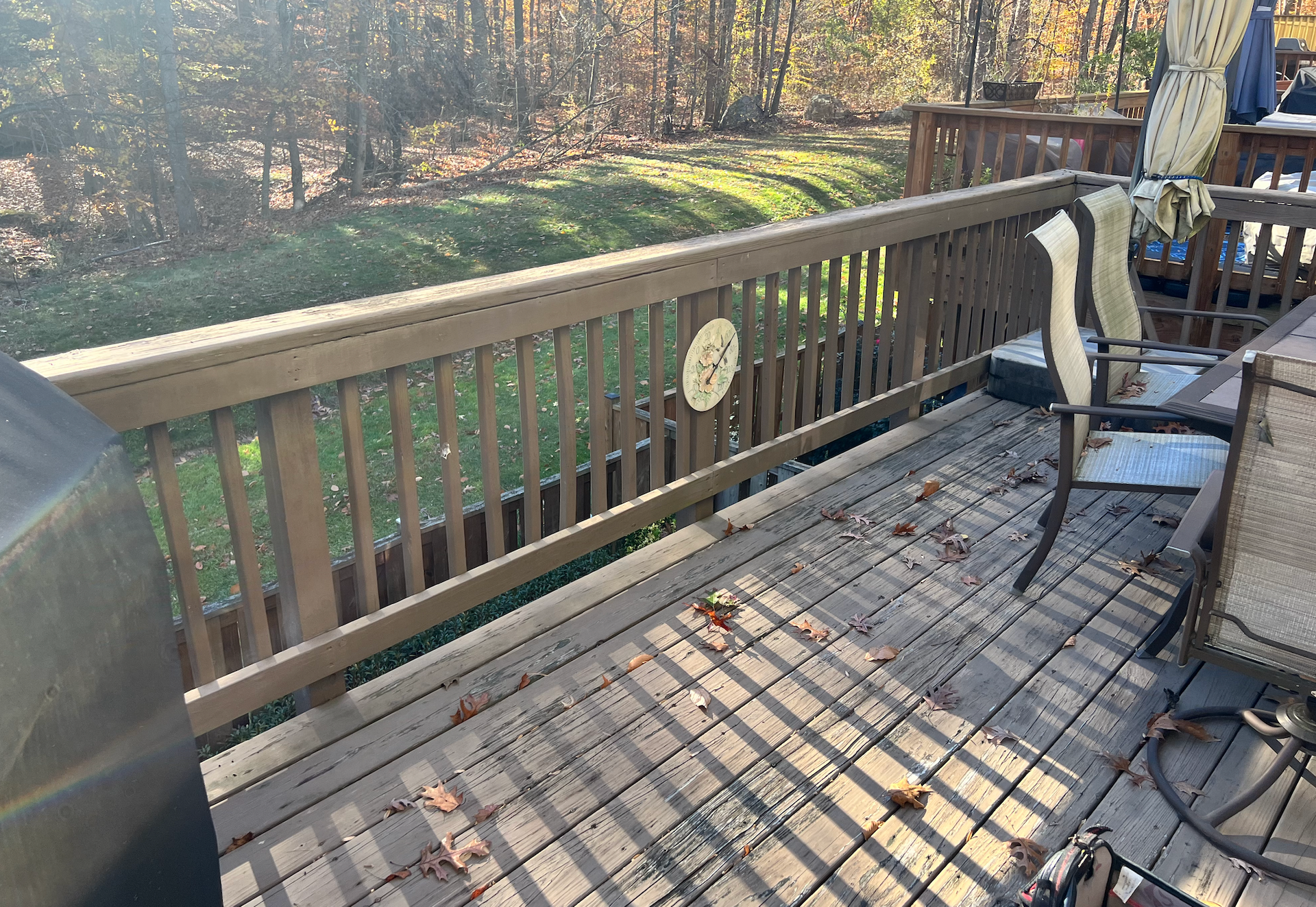 A wooden deck with a fence and chairs on it.