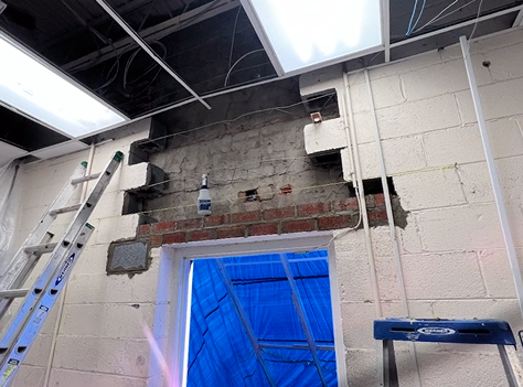 A ladder is sitting next to a brick wall in a room.