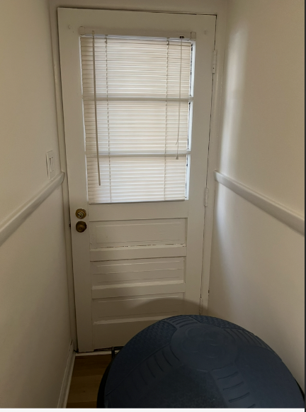 A white door with blinds on it is in a hallway.