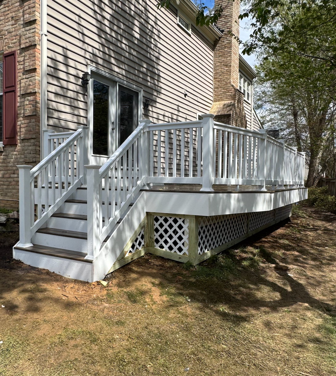 A white deck with stairs is in front of a house.
