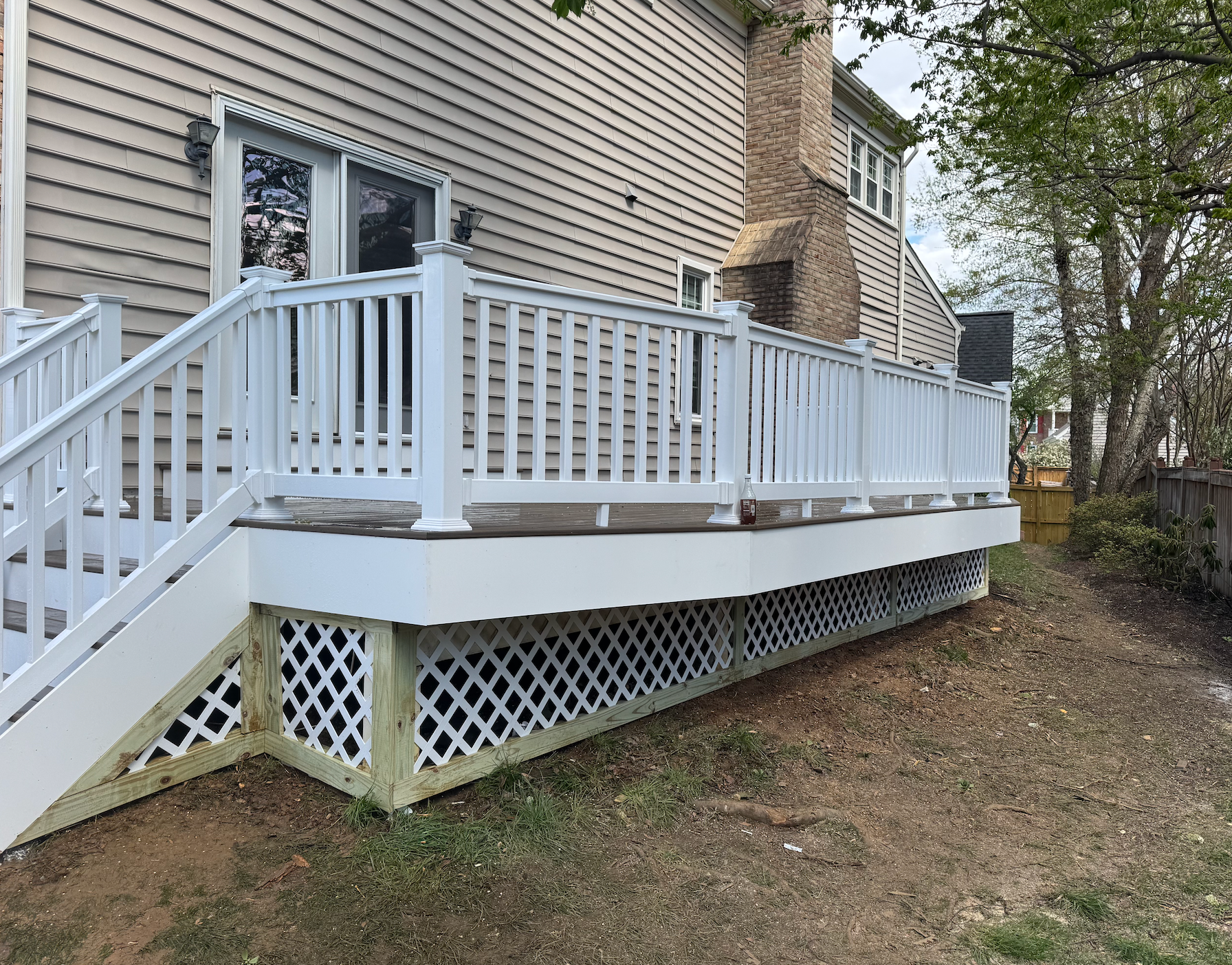 A white deck with stairs is in front of a house.
